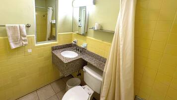 A bathroom with yellow walls, a white toilet, a sink with a mirror above it, and a shower curtain.