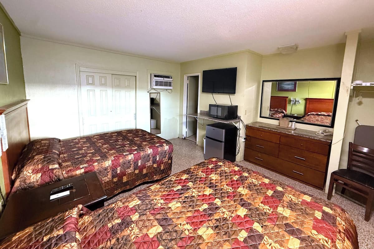 Een hotelkamer met twee bedden, een televisie, een dressoir, een spiegel en een airconditioning.