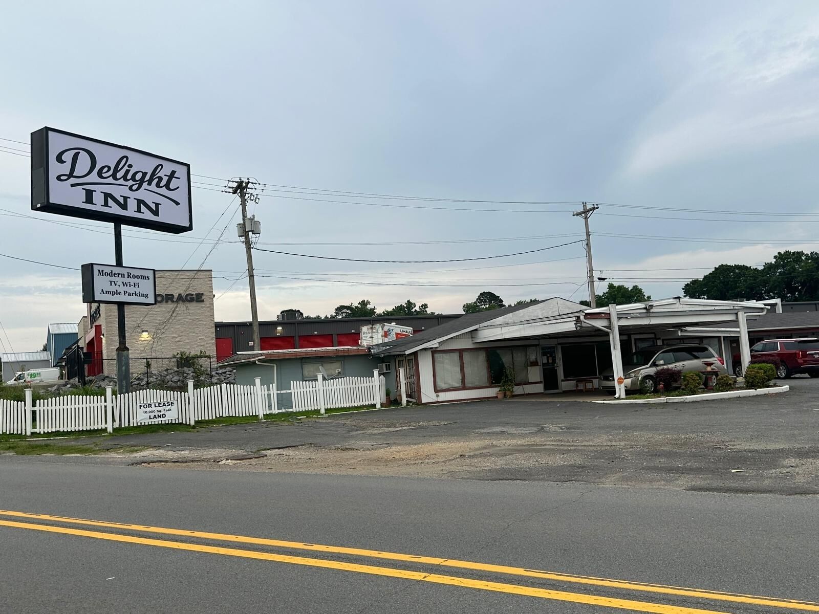 Un motel avec une enseigne indiquant « Delight INN » et une plus petite enseigne indiquant « Chambres modernes, télévision, Wi-Fi, grand parking ».