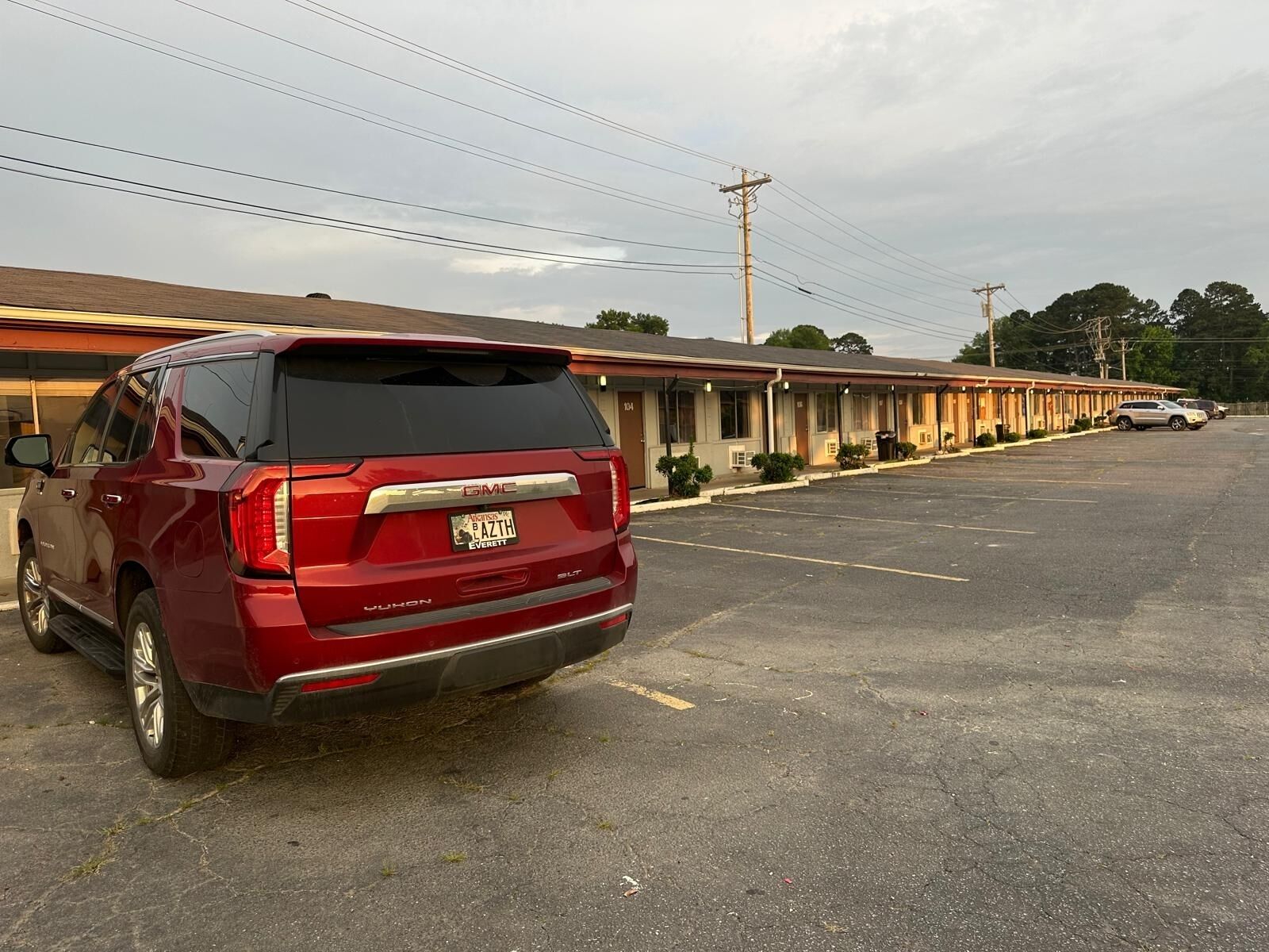 A red GMC Yukon SUV parked in a motel parking lot with a row of motel rooms in the background.
