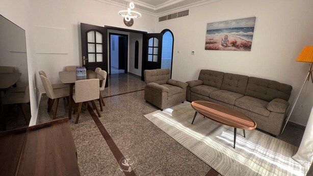 Un salon moderne comprenant un canapé, des fauteuils, une table basse et un coin repas avec une table et des chaises.
