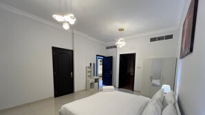 Une chambre moderne avec un grand lit, des murs blancs et une armoire intégrée.