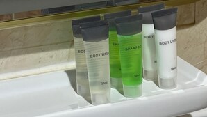 Une étagère de salle de bain avec quatre bouteilles de gel douche et de shampoing.