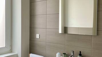 Een badkamer met een witte wastafel, een spiegel en een handdoekhouder.