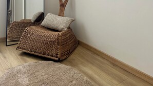 Habitación de esquina con una silla tejida, un espejo y una alfombra mullida.