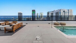 A rooftop terrace with a pool, seating area, and a city skyline view. - City Vibes with Spa & Gym in Sleek 1BR Retreat (Miami)