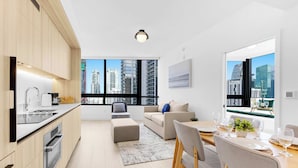 A modern apartment with a kitchen, dining area, and living space, featuring large windows with city views. - City Vibes with Spa & Gym in Sleek 1BR Retreat (Miami)