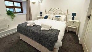 Ein Schlafzimmer mit einem großen Bett, zwei Nachttischen, einem Fenster mit Vorhängen und einer Heizung.