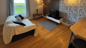 A bedroom with a bed, a TV, a small table, and a window with a view. - Crag Barn Cottage – Lake District Getaway by PolkaStays (Lake District)