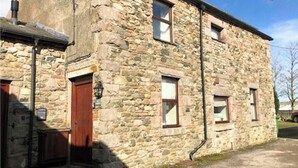 A stone building with a wooden door and multiple windows. - The Stables | Romantic Countryside Escape in the Lake District (Lake District)