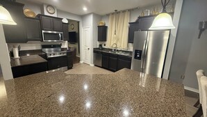Een moderne keuken met granieten aanrechtbladen, roestvrijstalen apparatuur en een centraal eiland.