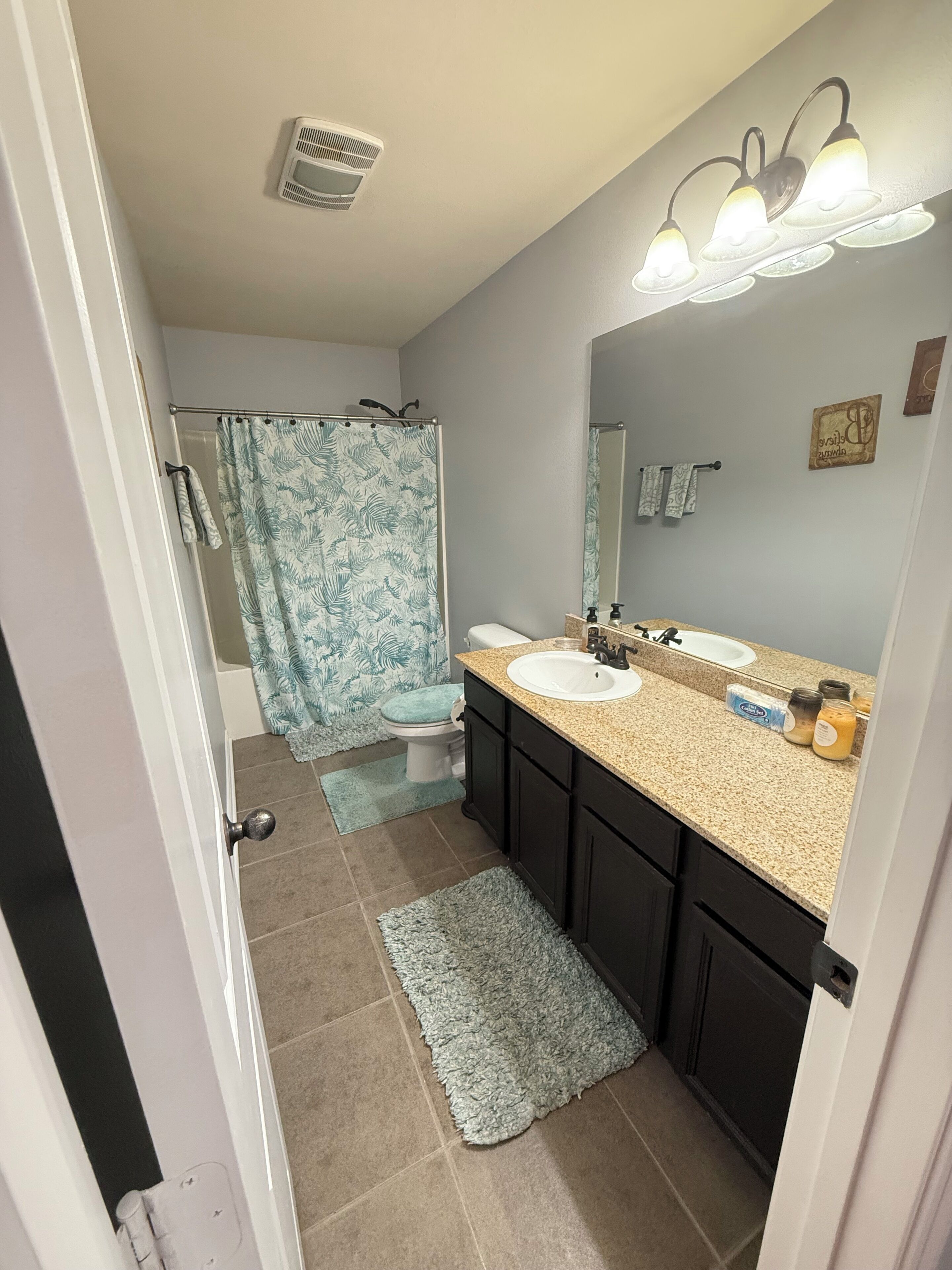 Une salle de bain avec un lavabo, un miroir et un rideau de douche.