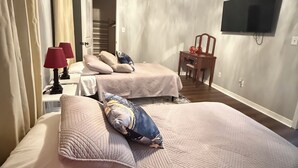 Een hotelkamer met twee bedden, een aan de muur bevestigde televisie en een kroonluchter.