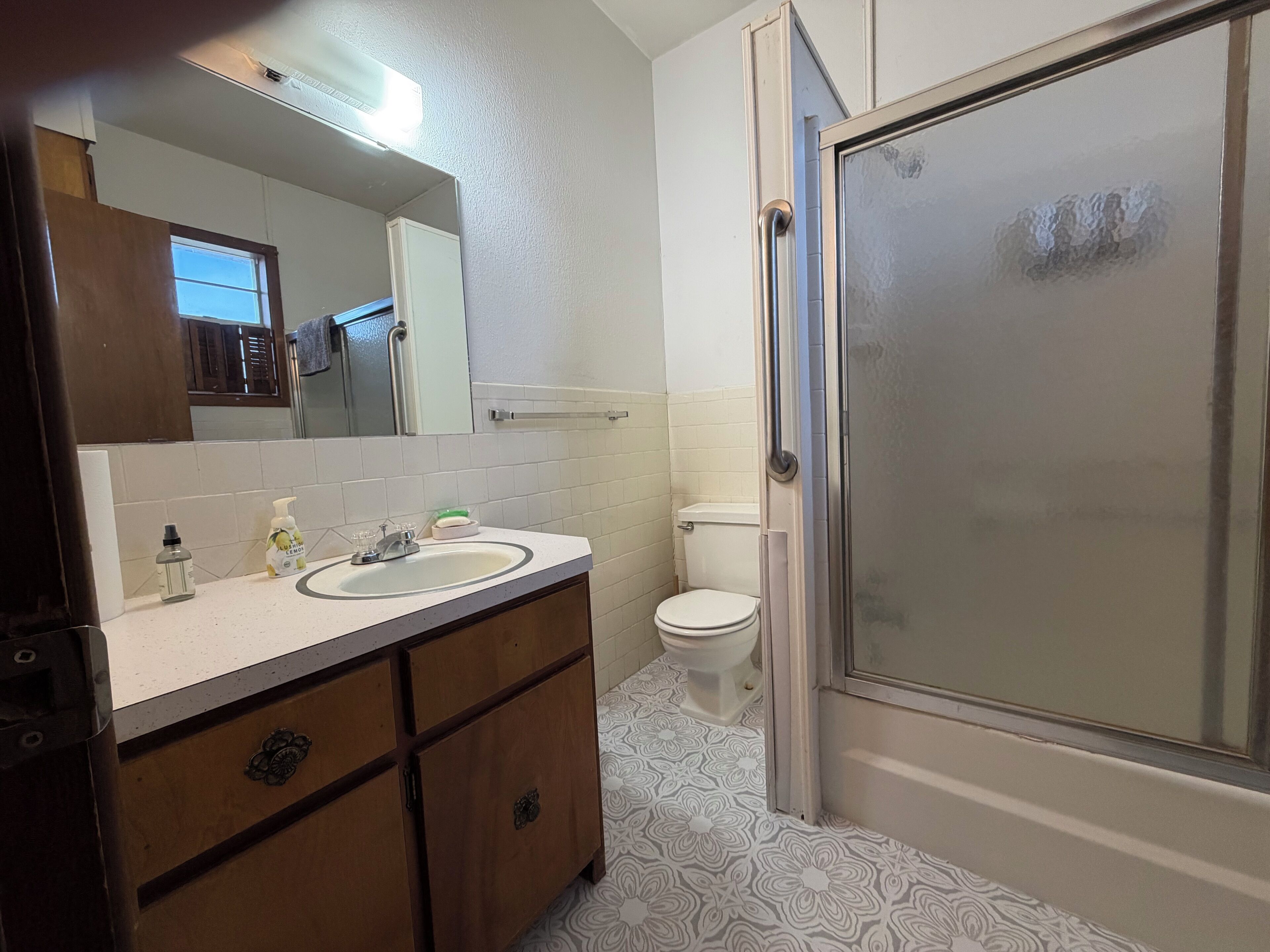 A bathroom with a sink, mirror, toilet, and shower.
