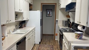 A compact kitchen with white cabinets, a microwave, a stove, and a sink.