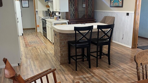 A kitchen with a central island, white cabinets, a microwave, and a ceiling fan.