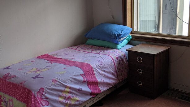Ein kleines Schlafzimmer mit einem Einzelbett, einem Schminktisch und einem Fenster.