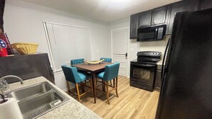A compact kitchen with a dining table, chairs, a sink, a microwave, and a refrigerator. - Deck the Halls (Clarksville)