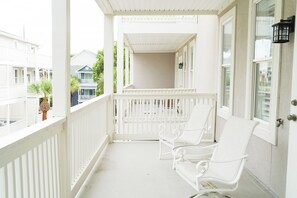 A white balcony with a railing, two white chairs, and a potted plant. - Large beach home w golf cart, minutes from beach! (St Simons Island)