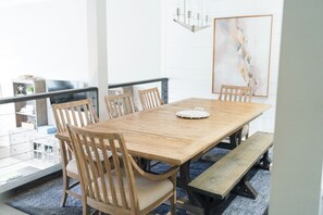 Een eetruimte met een houten tafel, zes stoelen, een bank en een kroonluchter.