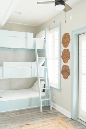 A room with a bunk bed, a ladder, a ceiling fan, and a door with a window. - Large beach home w golf cart, minutes from beach! (St Simons Island)