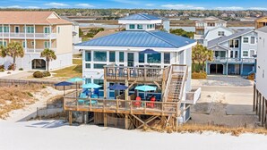 Ein Hotel direkt am Strand mit einer zweistöckigen Struktur, Außenplätzen und Blick auf Strand und Meer.