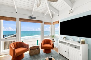 A room with a large TV, two armchairs, a coffee table, and a view of the beach. - Bonsai - Oceanfront Zen Retreat • 4BR • 5BA • Direct Beach Walkway • Epic Views (Oak Island)
