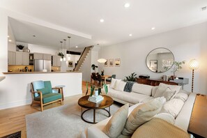 A modern living room with a sofa, a coffee table, and a dining area with chairs and a table. - Rittenhouse Gem Luxe 2BD 2.5BA Near the Square (Philadelphia)