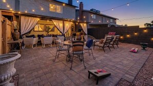 Ein Außenbereich mit Terrasse, Lichterketten, Korbmöbeln und einem Backsteinboden.