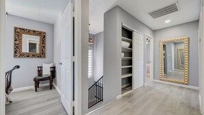 Ein Flur mit Stuhl, Spiegel und Treppe.