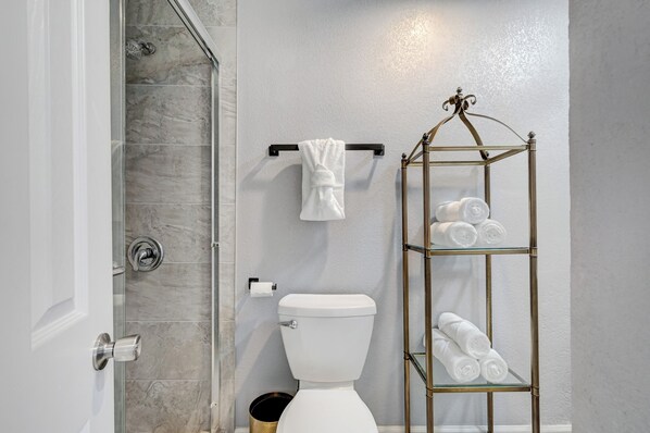 A bathroom with a glass shower enclosure, a toilet, a towel rack, and a glass towel rack with towels. - Travelers Dream, 4bd Spacious + Cornhole + Free Uber Airport Pickup (Las Vegas)
