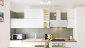 Une cuisine moderne avec des meubles blancs, un four à micro-ondes, un évier et un vase rempli de fleurs posé sur le plan de travail.
