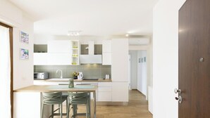 Une cuisine moderne avec des meubles blancs, un plan de travail en bois et un coin repas équipé de deux chaises.