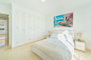 Un dormitorio con una cama grande, un armario blanco y un cuadro de un barco en la pared.