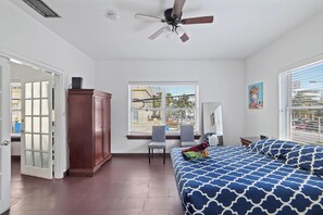 Une chambre à coucher comprenant un lit, un bureau, une chaise, une armoire et une fenêtre avec des stores.
