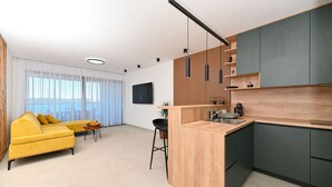 Un appartement moderne avec un canapé jaune, une cuisine dotée de meubles sombres et un coin repas comprenant une table et des chaises.