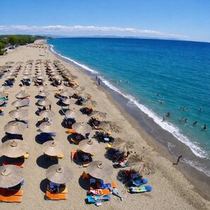 A beach with rows of sunbeds and umbrellas, a clear blue sea, and a distant mountain range. - Diana s House 2 - Gytheio Sandy Beach Haven (East Mani)