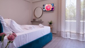 A bedroom with a bed, a TV, a round mirror, a shelf with small items, and a window with curtains. - Diana s House 2 - Gytheio Sandy Beach Haven (East Mani)