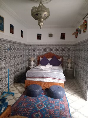 A bedroom with a patterned tile wall, a bed with a wooden headboard, and a decorative chandelier. - DAR MARGOT MARRAKECH (Marrakesh)