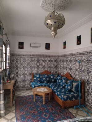 A living room with a patterned wall, a sofa, a coffee table, and a hanging light fixture. - DAR MARGOT MARRAKECH (Marrakesh)