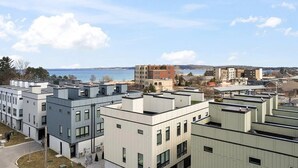 A modern building complex with multiple floors, large windows, and a view of the sea.