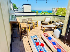 A rooftop terrace with outdoor furniture, a table, and a view of the sea.