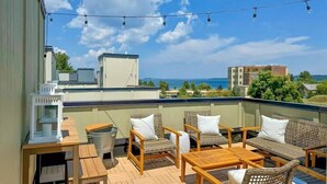 A rooftop terrace with wicker furniture, a table, and string lights.