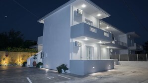 Un bâtiment moderne à deux étages, doté de balcons, d’une entrée couverte et d’un éclairage extérieur.