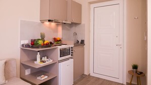 Une cuisine compacte équipée d’un four à micro-ondes, d’un four traditionnel et d’un panier à fruits posé sur le plan de travail.