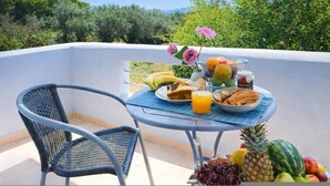 Un balcon avec une table préparée pour le petit-déjeuner, comprenant des fruits, du pain et du jus.