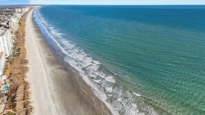 A coastal beach with a clear view of the ocean, a sandy shoreline, and buildings along the coast. - Blocks to Beach • Hot Tub • Pool • RV Parking • Family Friendly (North Myrtle Beach)