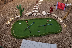 A miniature golf course with a green putting surface, two golf holes, and surrounding landscaping. - Canyon Lake Retreat | Hot Tub + Arcade + Mini Golf | Sleeps 8 | Near Boat Ramp (Canyon Lake)