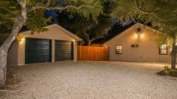 Un bâtiment à deux étages avec une allée en gravier, deux portes de garage et une clôture en bois.