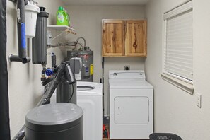 A compact laundry room with a washing machine, a dryer, a water heater, and a water filtration system. - Canyon Lake Retreat | Hot Tub + Arcade + Mini Golf | Sleeps 8 | Near Boat Ramp (Canyon Lake)